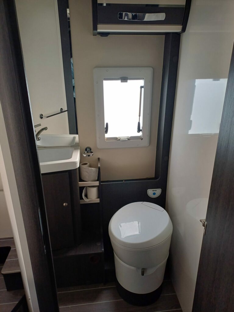 Compact bathroom of a CI 67 integral motorhome with a toilet, a sink and a small window providing light