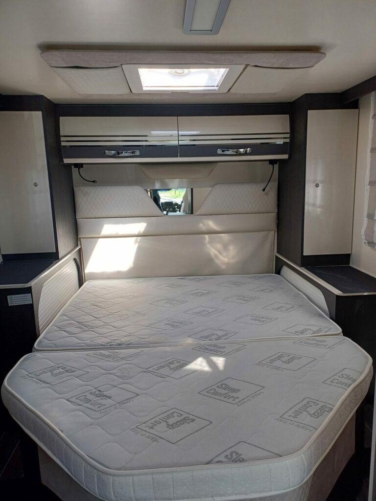 Bedroom with a comfortable double bed and built-in storage in a CI 67 integral camper van